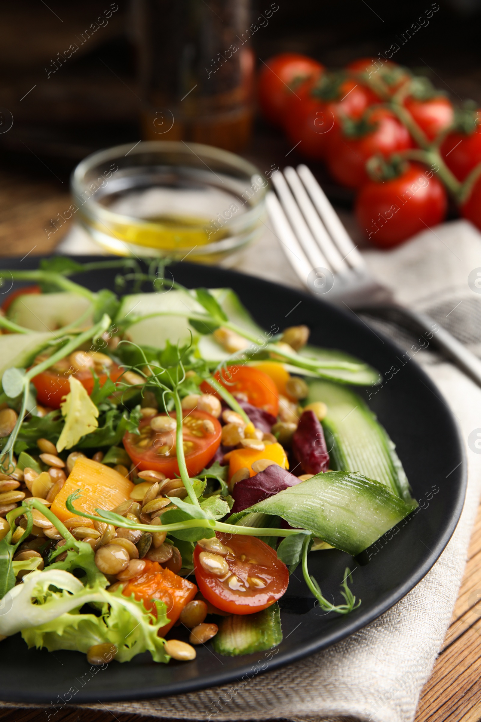 Photo of Delicious salad with lentils and vegetables served on wooden table, closeup