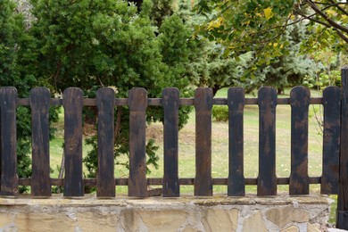 Low wooden shabby fence near trees outdoors