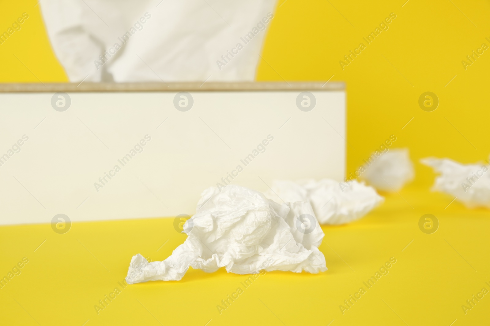 Photo of Used paper tissue and holder on yellow background, closeup