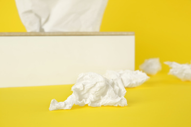 Photo of Used paper tissue and holder on yellow background, closeup