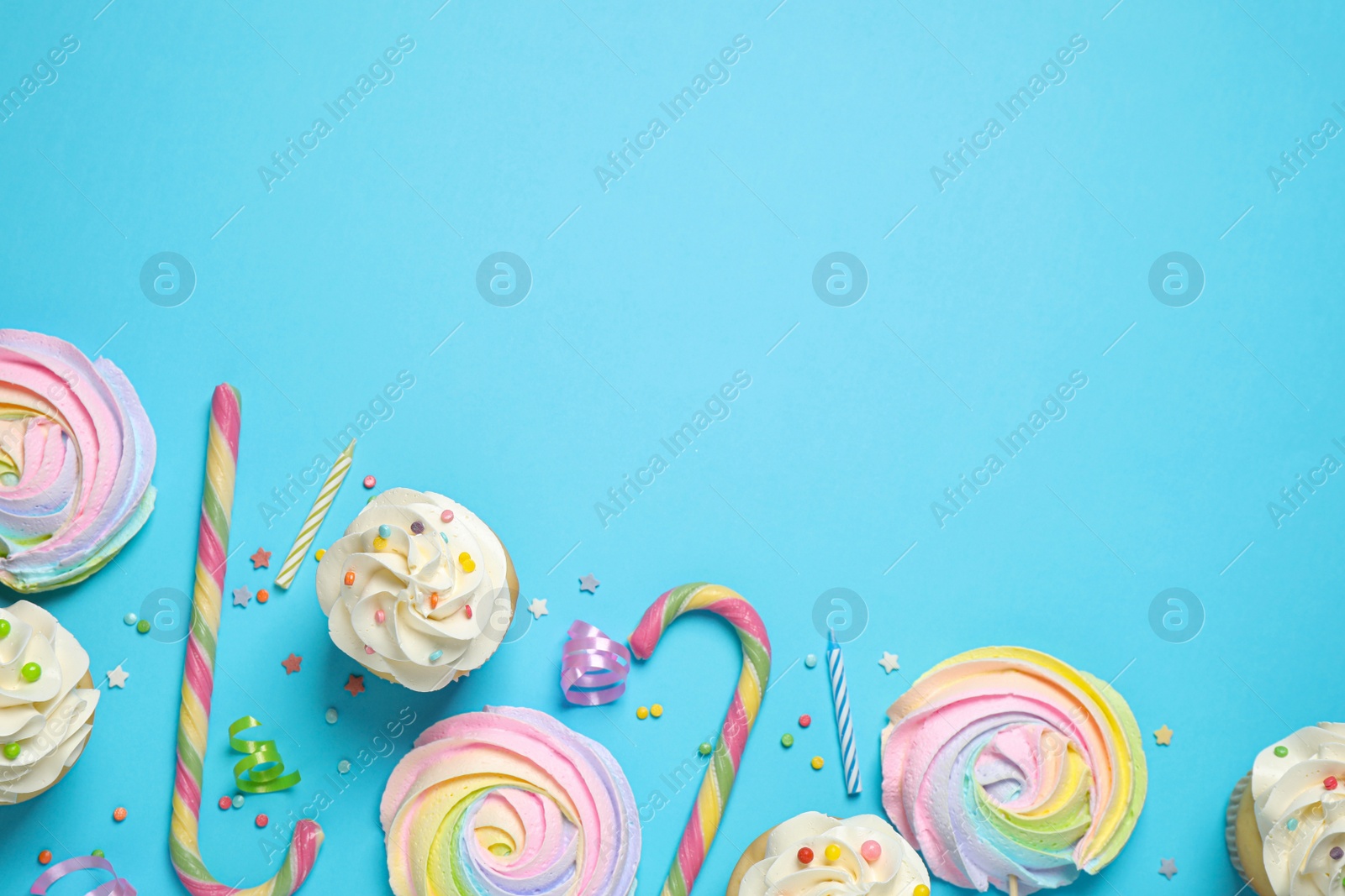 Photo of Flat lay composition with cupcakes on light blue background, space for text. Birthday party