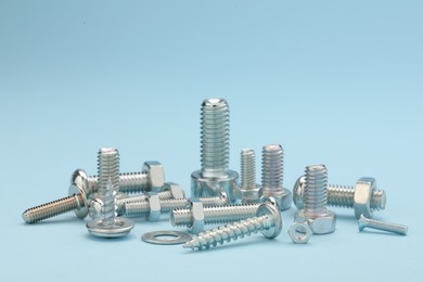 Many different fasteners on light blue background, closeup