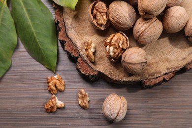 Photo of Tasty walnuts and fresh leaves on wooden table, top view