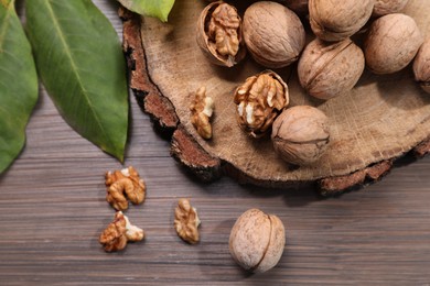 Tasty walnuts and fresh leaves on wooden table, top view