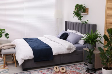 Photo of Stylish bedroom with double bed and beautiful green houseplants. Modern interior