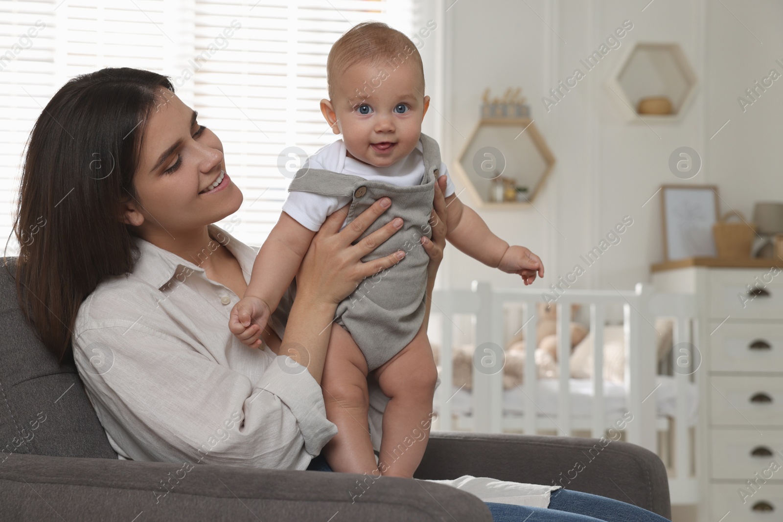 Photo of Happy young mother with her baby in armchair at home