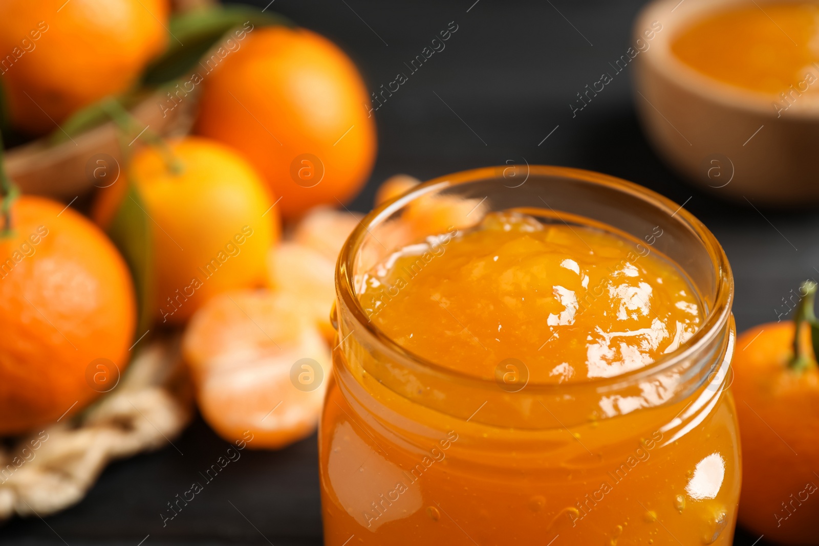 Photo of Tasty tangerine jam in glass jar on table, closeup. Space for text