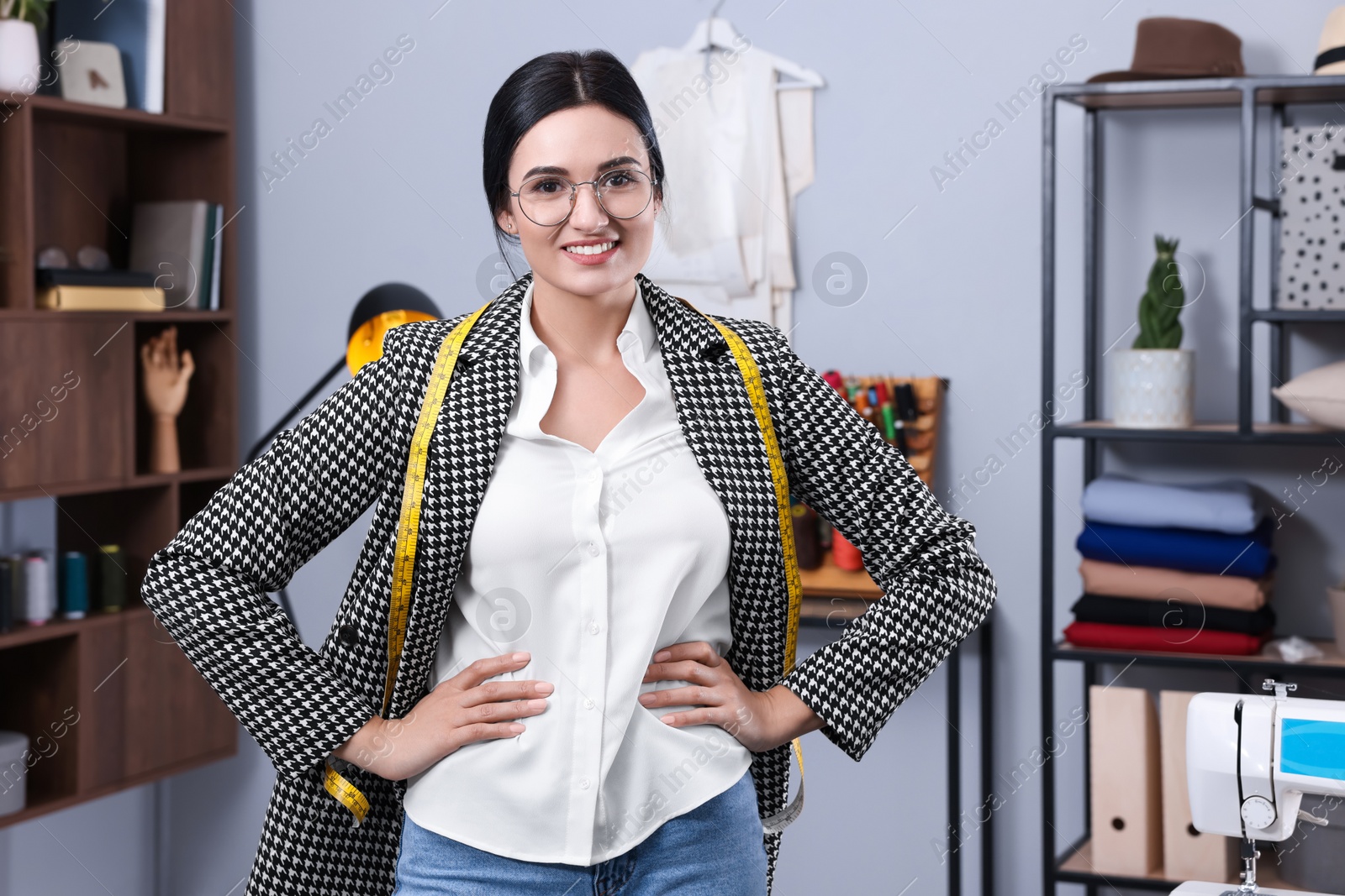 Photo of Happy dressmaker with measuring tape in workshop