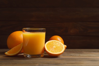 Photo of Glass of orange juice and fresh fruits on wooden table