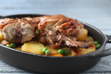 Photo of Tasty cooked rabbit with vegetables in baking dish on grey wooden table, closeup