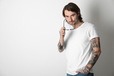 Young man with tattoos on arms against white background
