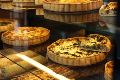 Photo of Different delicious quiches on counter in bakery shop, closeup