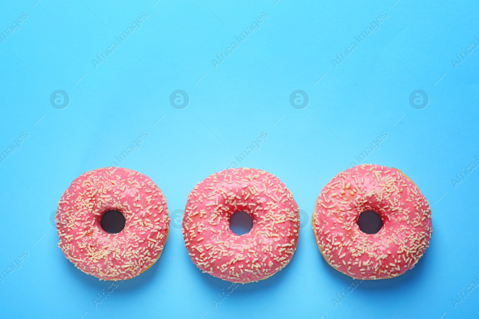 Photo of Delicious glazed doughnuts on color background, top view