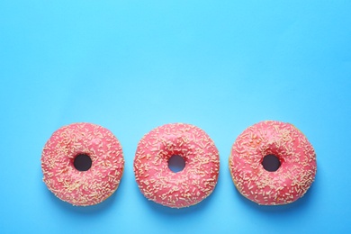 Delicious glazed doughnuts on color background, top view