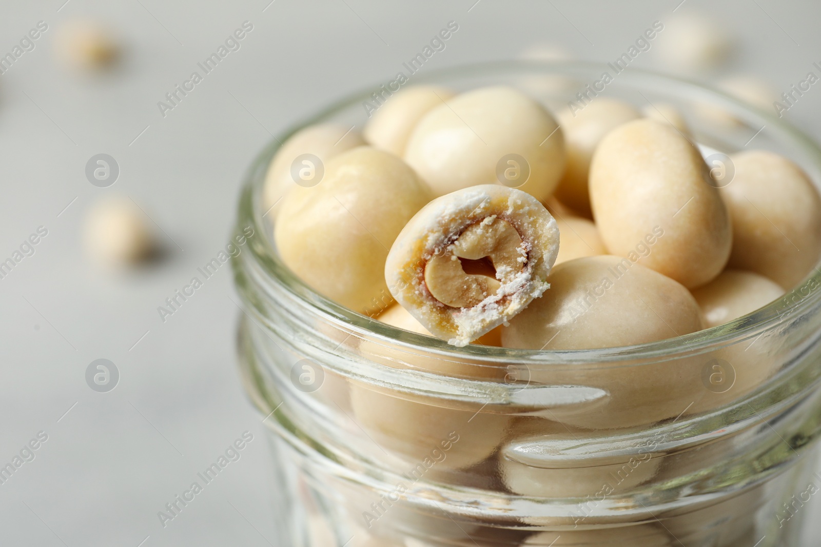 Photo of Glass jar with tasty sweets on light table, closeup