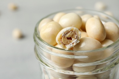 Glass jar with tasty sweets on light table, closeup