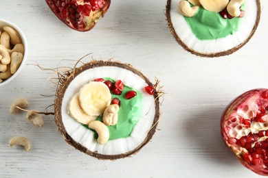 Photo of Flat lay composition with yummy spirulina smoothie in coconuts and pomegranate on wooden background