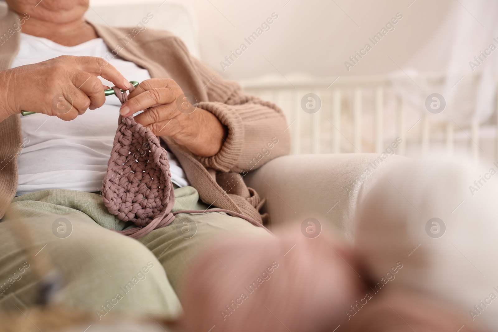 Photo of Elderly woman crocheting at home, closeup. Creative hobby