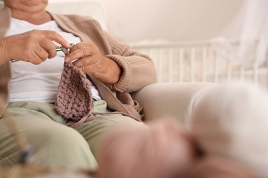 Elderly woman crocheting at home, closeup. Creative hobby