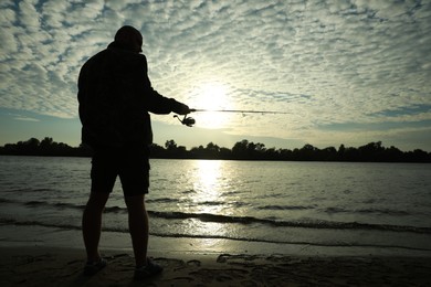 Photo of Fisherman with rod fishing at riverside, space for text