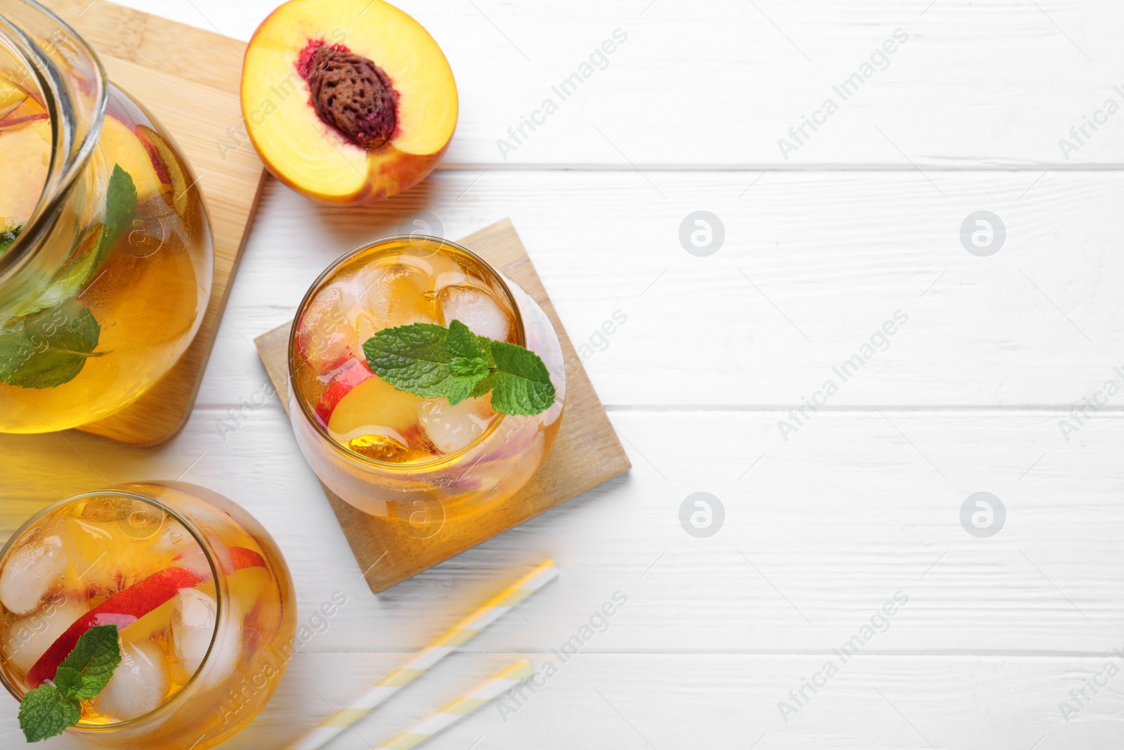 Photo of Delicious peach lemonade made with soda water on white wooden table, flat lay. Space for text