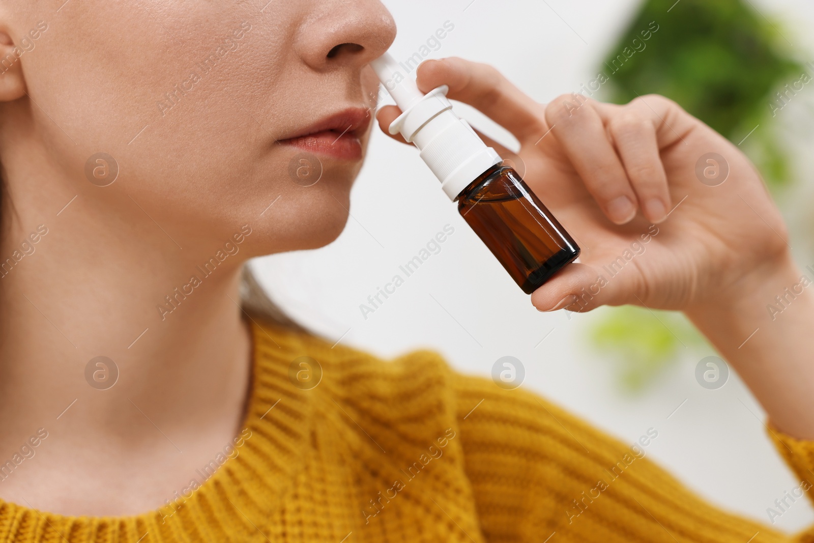 Photo of Medical drops. Young woman using nasal spray indoors, closeup