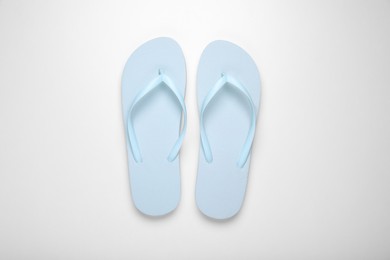 Photo of Light blue flip flops on white background, top view