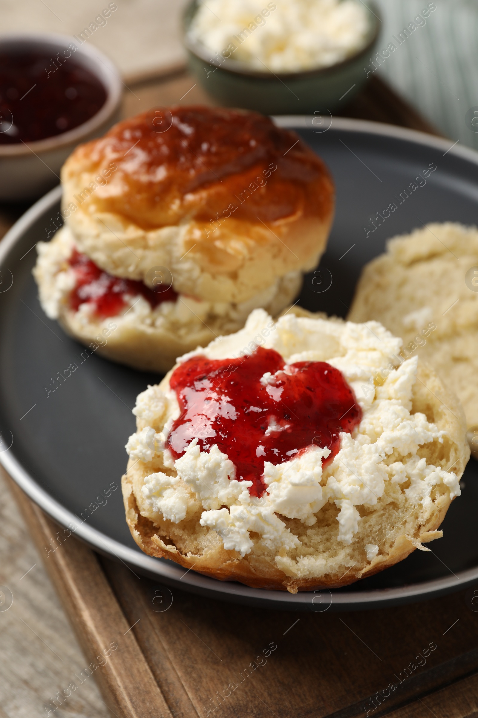 Photo of Freshly baked soda water scones with cranberry jam and butter on wooden table, closeup