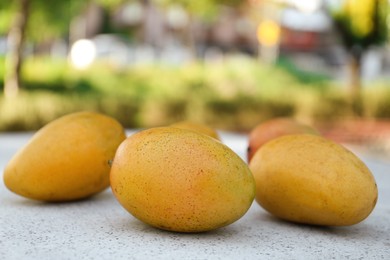 Photo of Delicious ripe juicy mangos on table outdoors