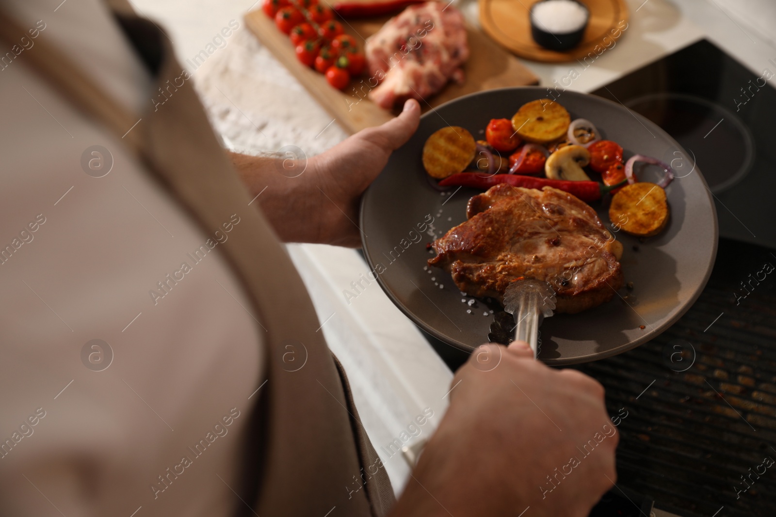 Photo of Man with tasty meat and vegetables cooked on frying pan, above view