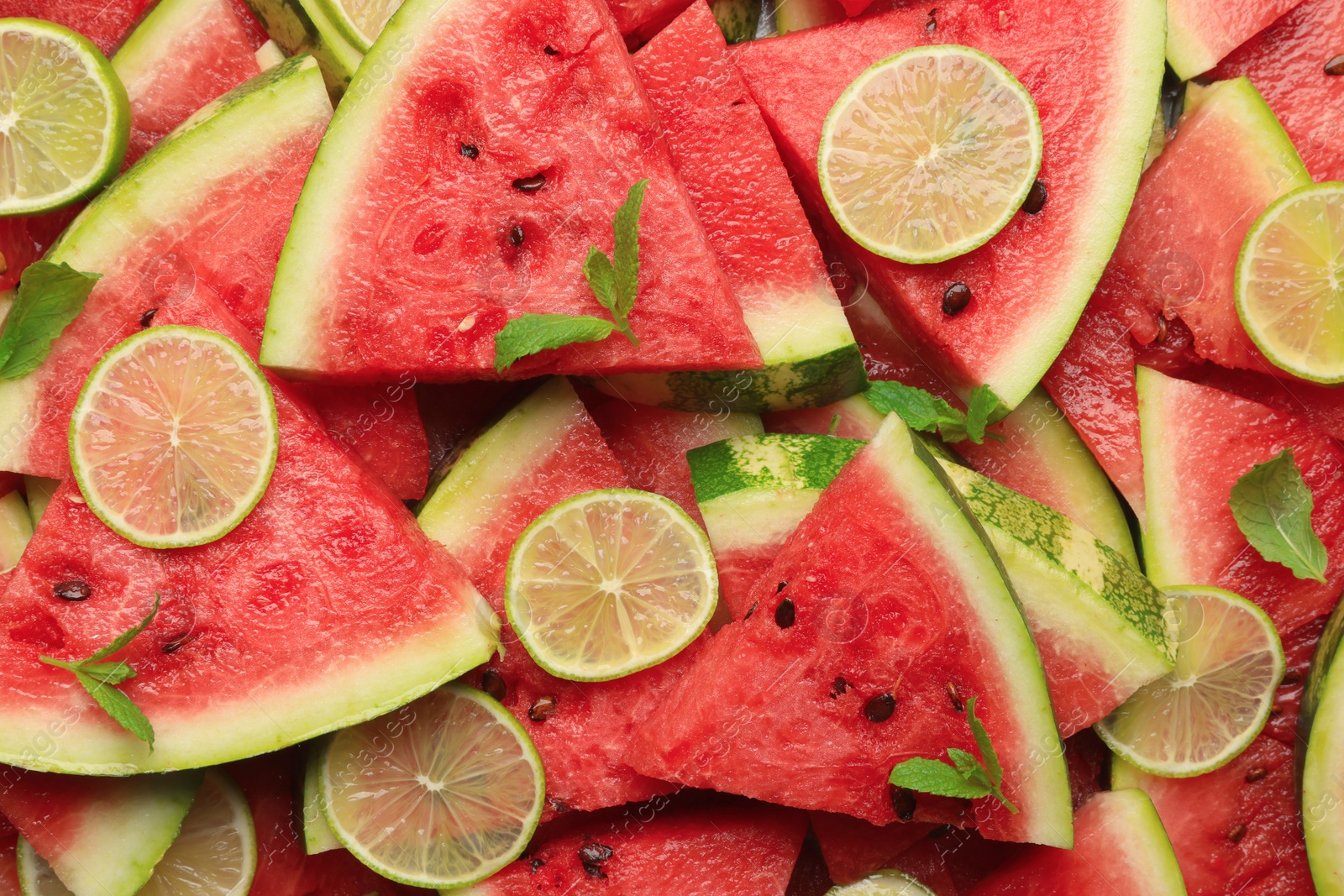 Photo of Slices of juicy watermelon with lime and mint as background, top view