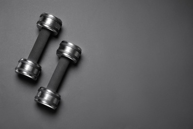 Metal dumbbells on black background, flat lay. Space for text