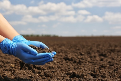 Woman holding pile of soil outdoors, closeup. Space for text