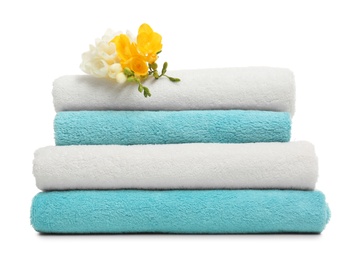 Stack of clean folded towels with flowers on white background