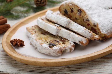 Photo of Traditional Christmas Stollen with icing sugar on white wooden table, closeup