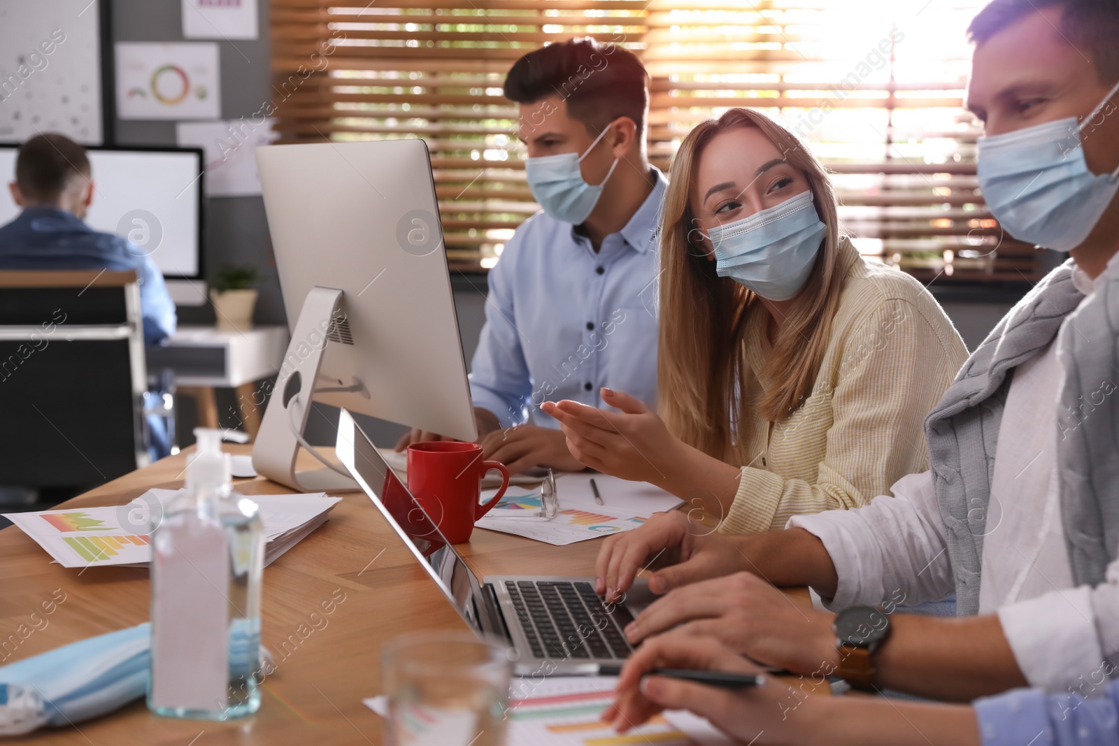 Photo of Coworkers with masks in office. Protective measure during COVID-19 pandemic