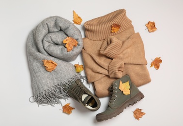 Photo of Composition with warm sweater and dry leaves on white background, top view. Autumn season