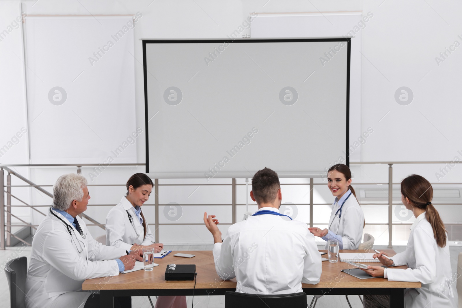 Photo of Team of doctors using video projector during conference indoors