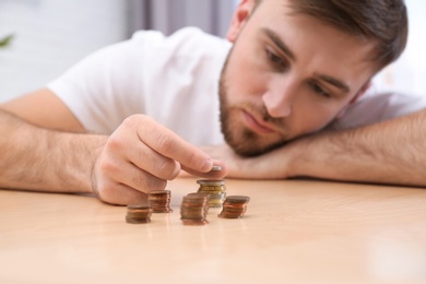 Photo of Sad young man counting money at home, closeup
