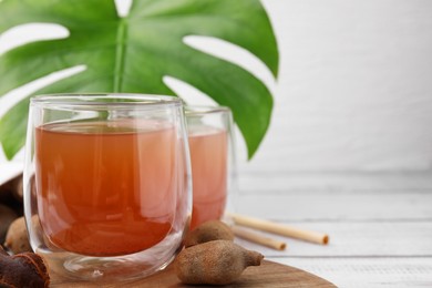 Tamarind juice and fresh fruits on white wooden table, closeup. Space for text