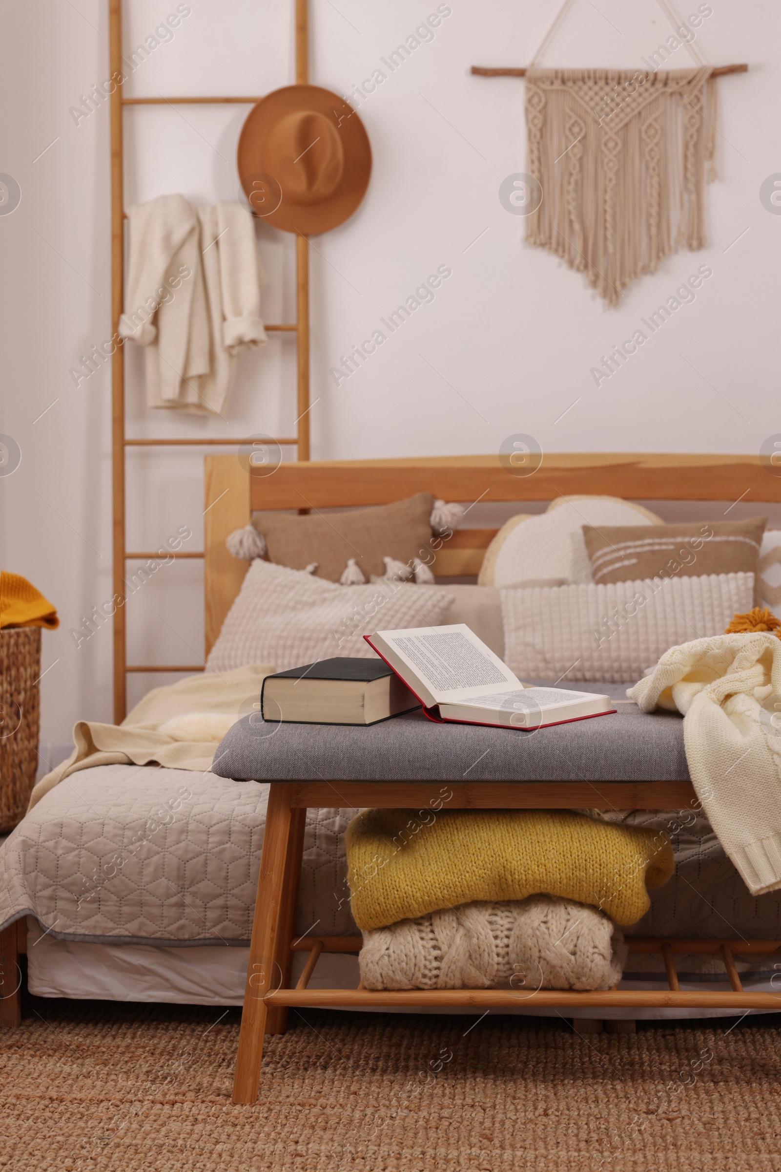 Photo of Large comfortable bed with soft sweaters, pillows and blanket in room. Home textile