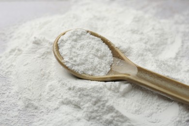 Pile of baking powder and spoon on table, closeup