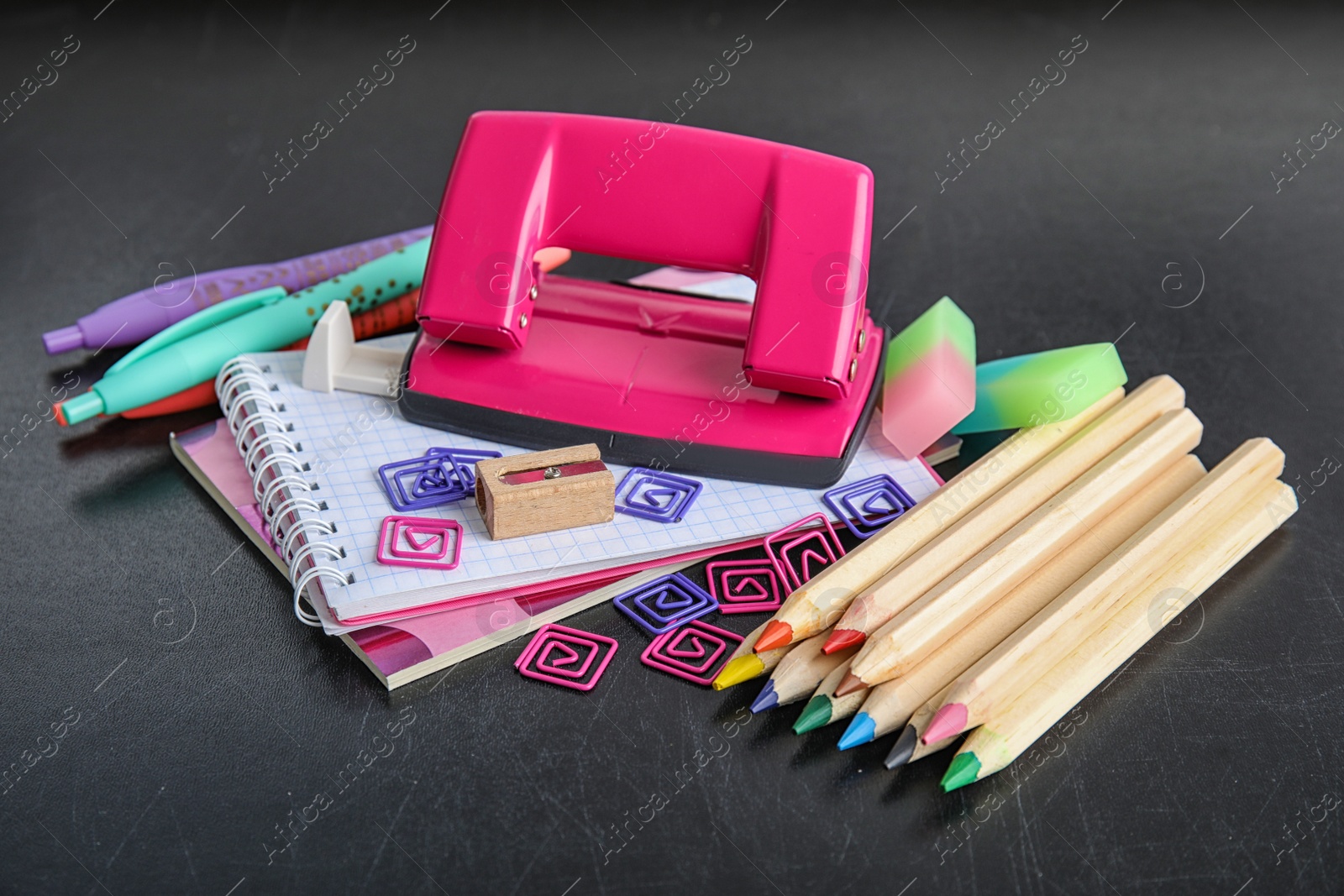 Photo of Different colorful stationery on chalkboard surface. Back to school
