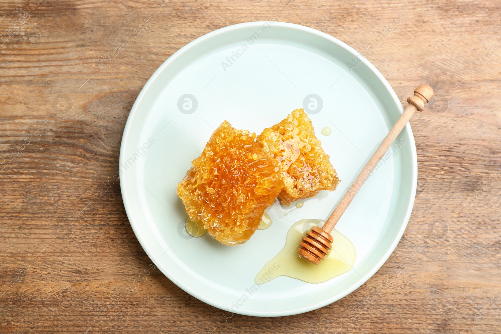 Photo of Tasty honey and combs on wooden table, top view