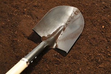 Photo of Metal shovel on fertile soil. Gardening tool