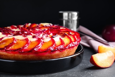 Photo of Delicious cake with plums on grey table, closeup