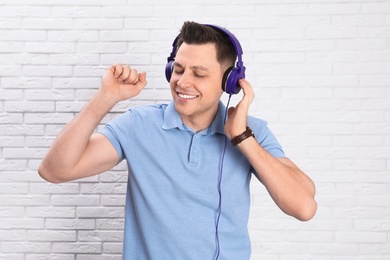 Photo of Man enjoying music in headphones against brick wall