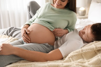 Young pregnant woman with her husband in bedroom, closeup