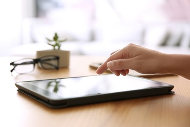 Photo of Woman working with modern tablet at wooden table, closeup