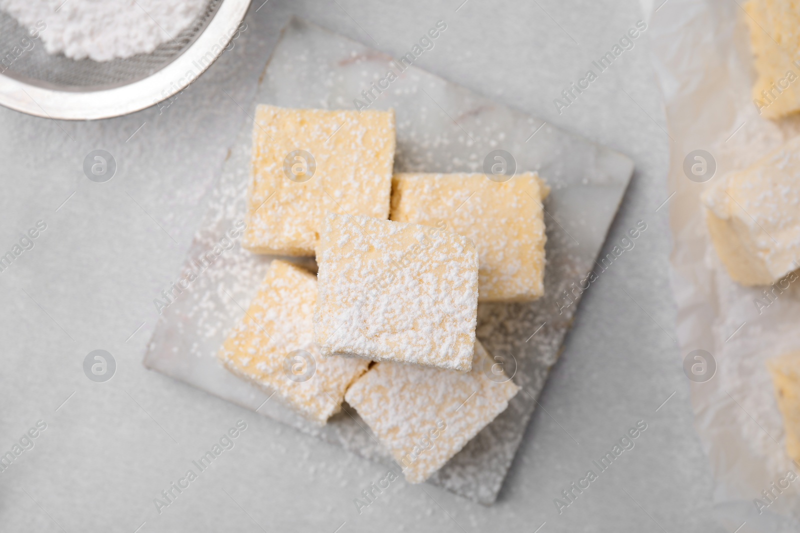 Photo of Delicious sweet marshmallows with powdered sugar on light grey table, flat lay